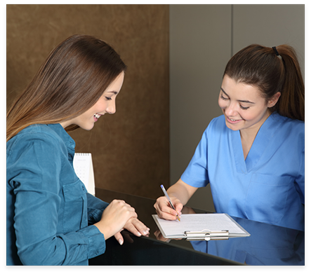 Dental team member showing a clipboard to a patient at desk