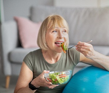 older woman eating salad with dental implants