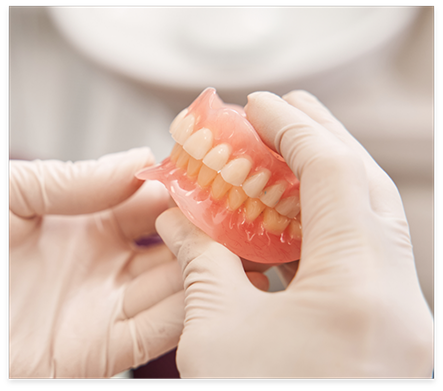 Gloved hands holding a set of dentures