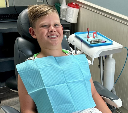 Young girl in dental chair smiling at her dentist
